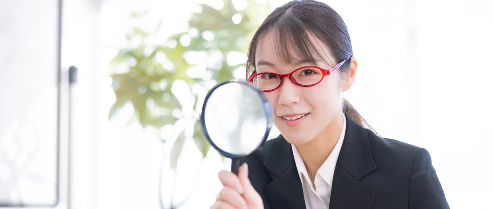 拡大鏡を持った女性会社員の画像